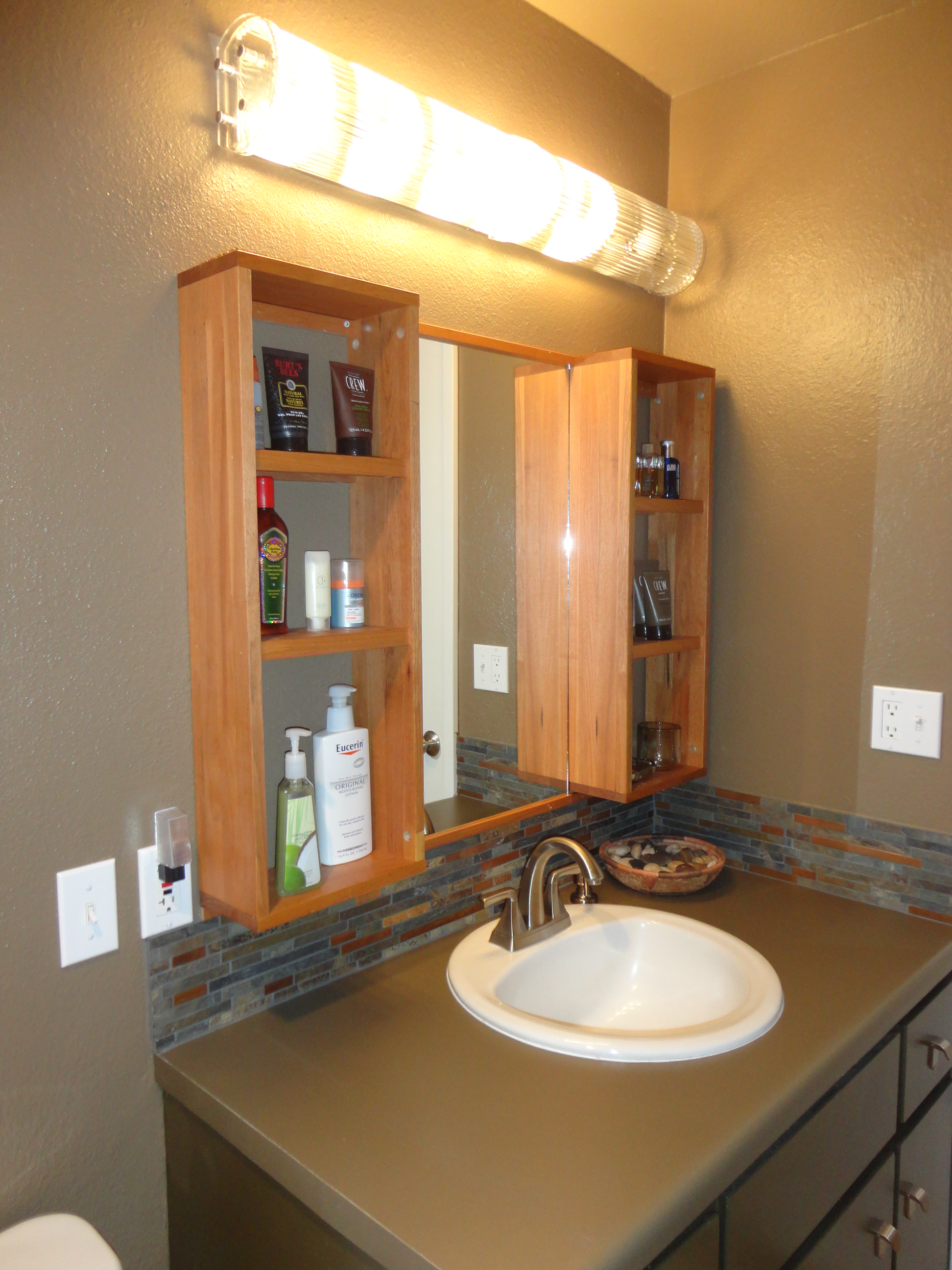 Custom wood bathroom vanity cabinet built around a mirror
