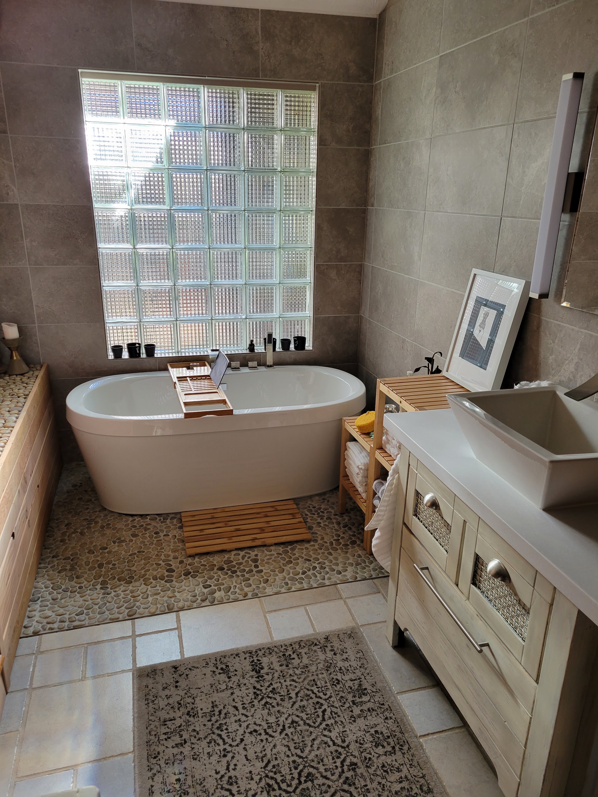 Remodeled bathroom with a freestanding soaking tub and glass block window